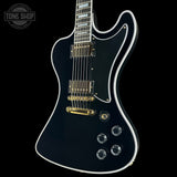 Black electric guitar with gold hardware on a black background, featuring 'Tone Shop' branding.