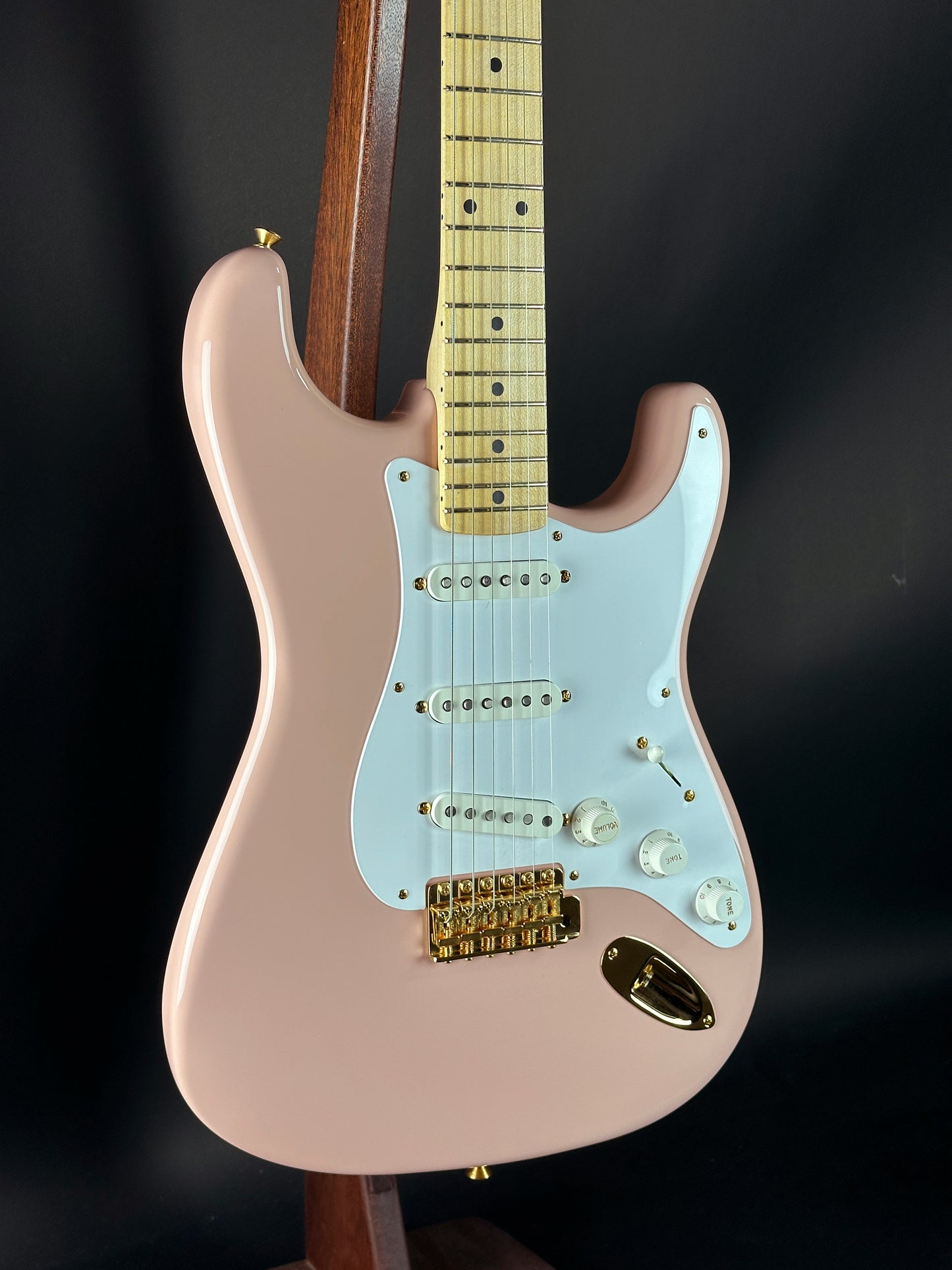 Pink electric guitar with a black background