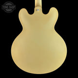 The back of a matte yellow electric guitar body, shown against a solid black background with a Tone Shop watermark in the top left corner.