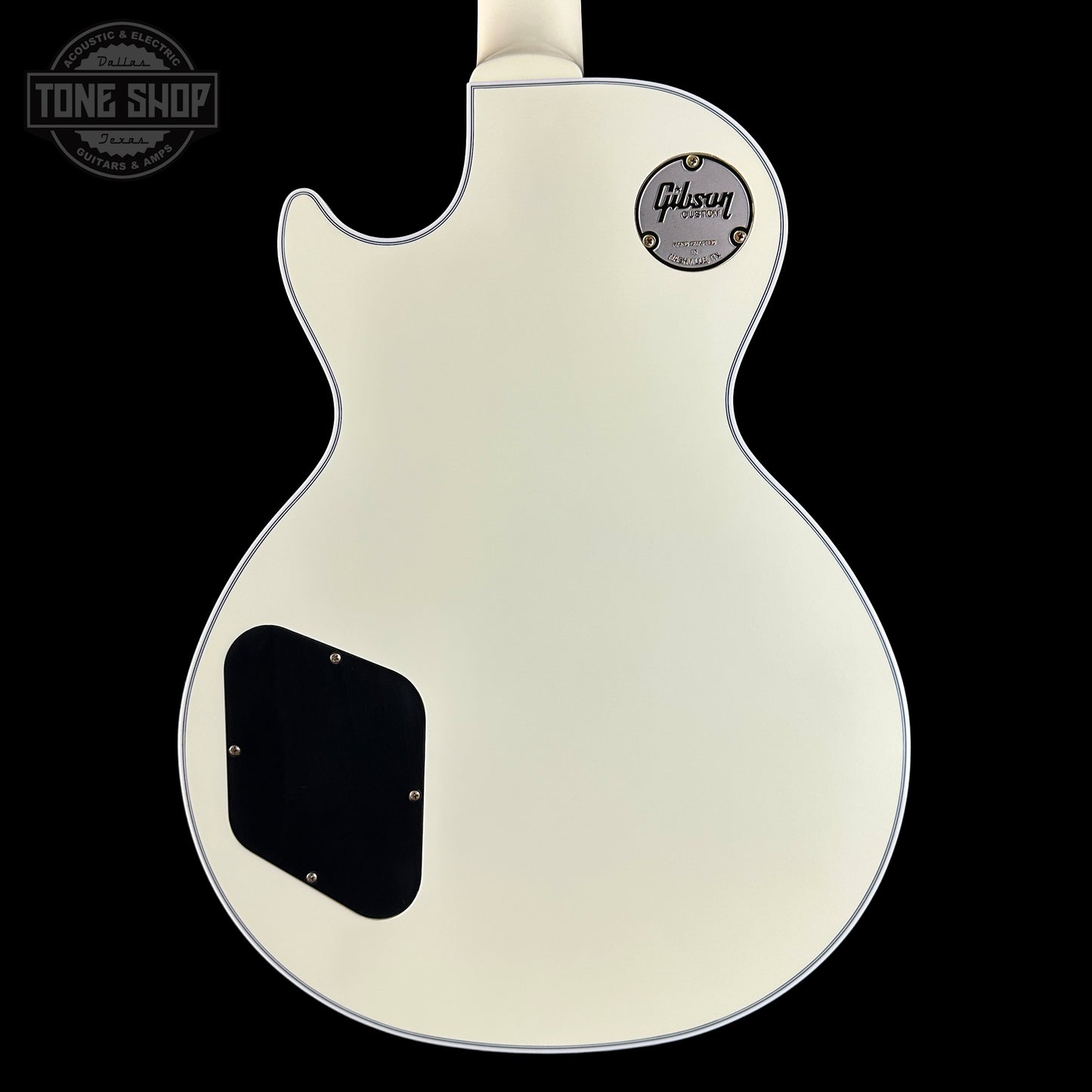 Back view of a Gibson electric guitar with a white finish on a black background.