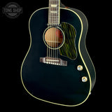 A black acoustic guitar with a glossy finish, cream binding, and a green-and-black striped pickguard, shown against a black background with a Tone Shop watermark in the top left.