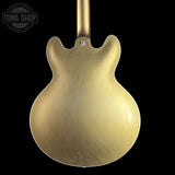 Close-up of a gold guitar body with 'Tone Shop' branding in the corner.