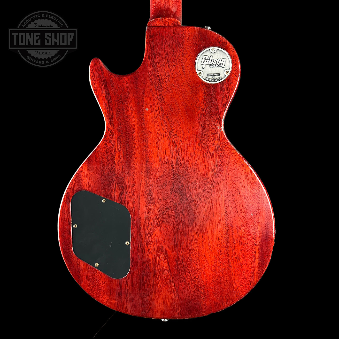 Back view of a red electric guitar with a visible brand logo on a black background.