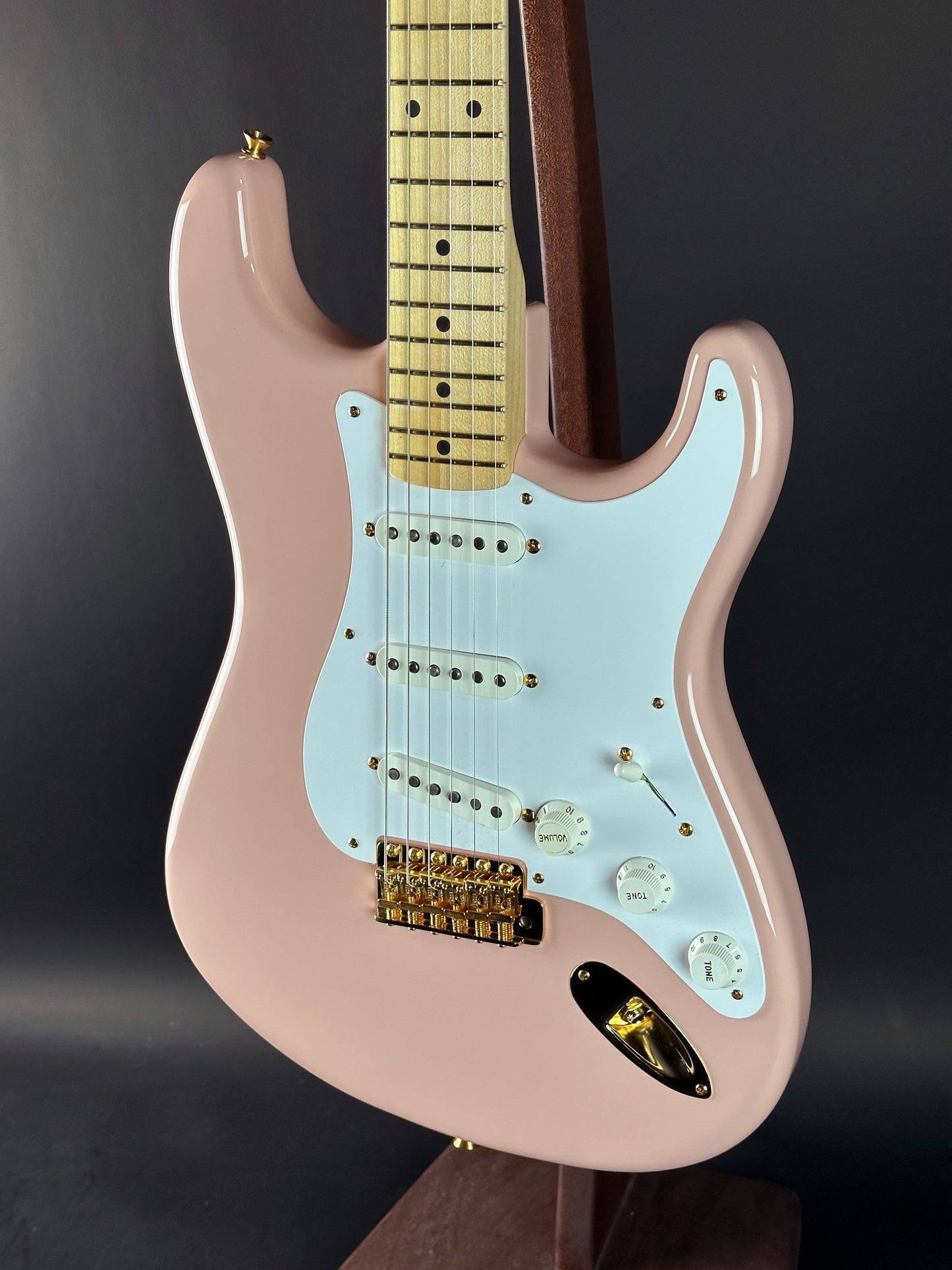 Electric guitar with a light blue pickguard and pink body on a dark background