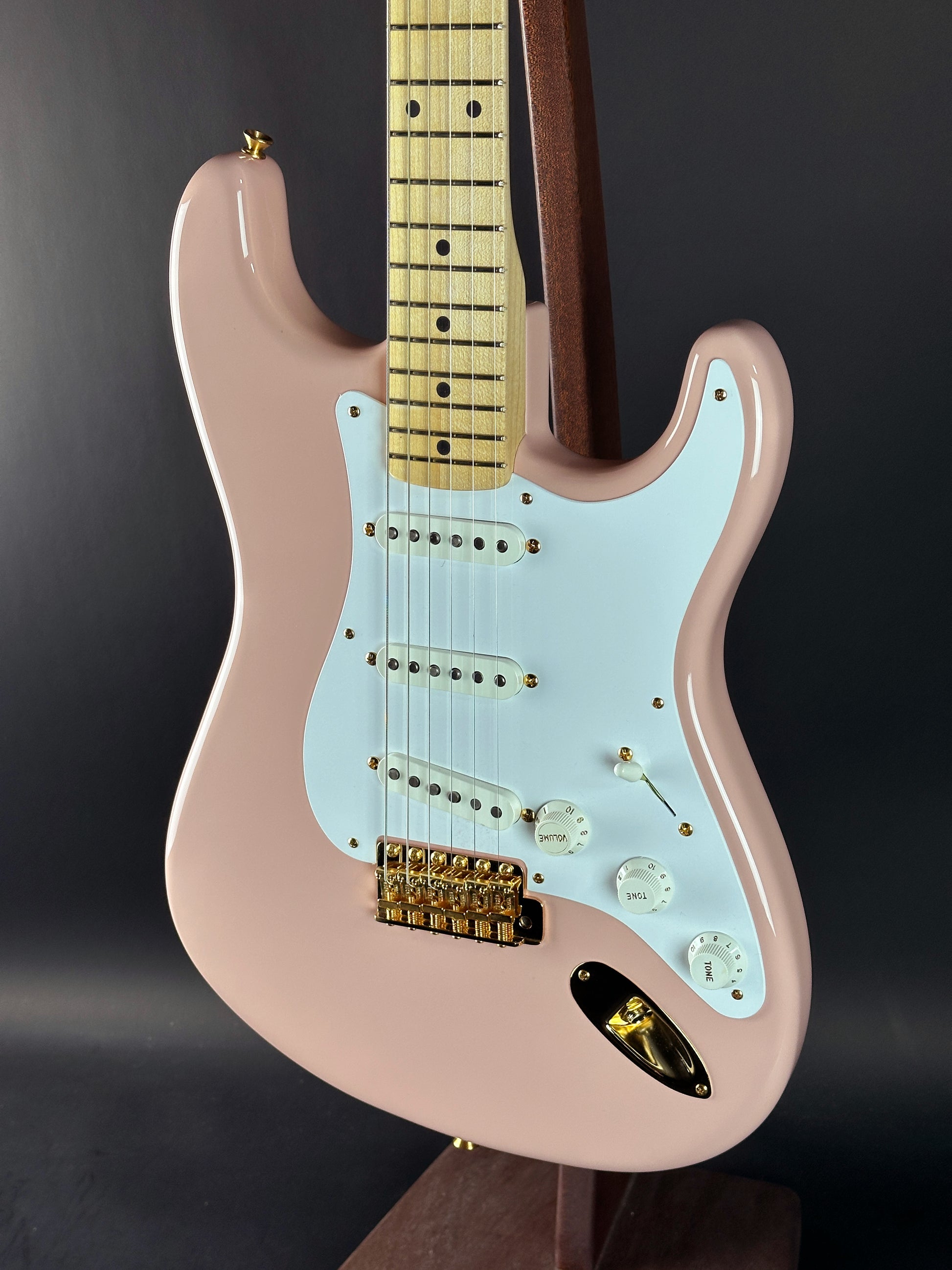 Electric guitar with a light blue pickguard and pink body on a dark background