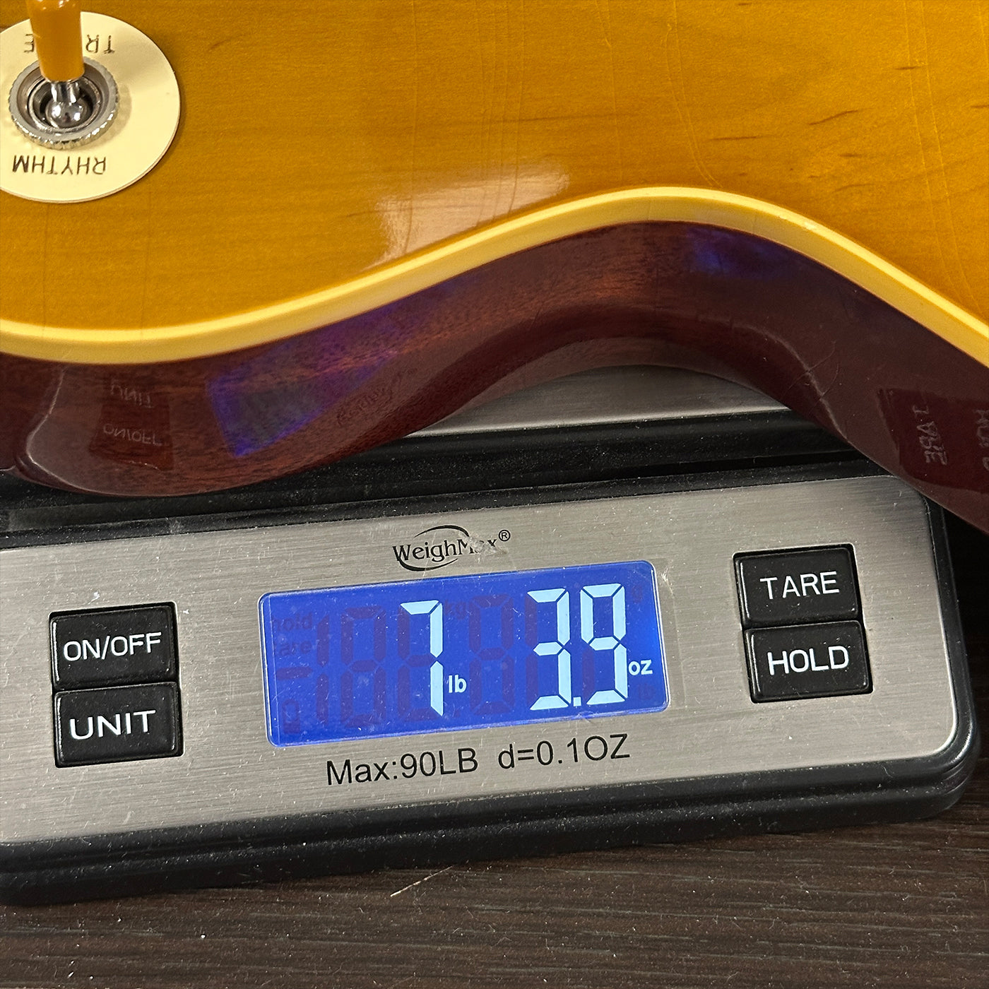 Guitar being weighed on a digital scale with a display showing weight.
