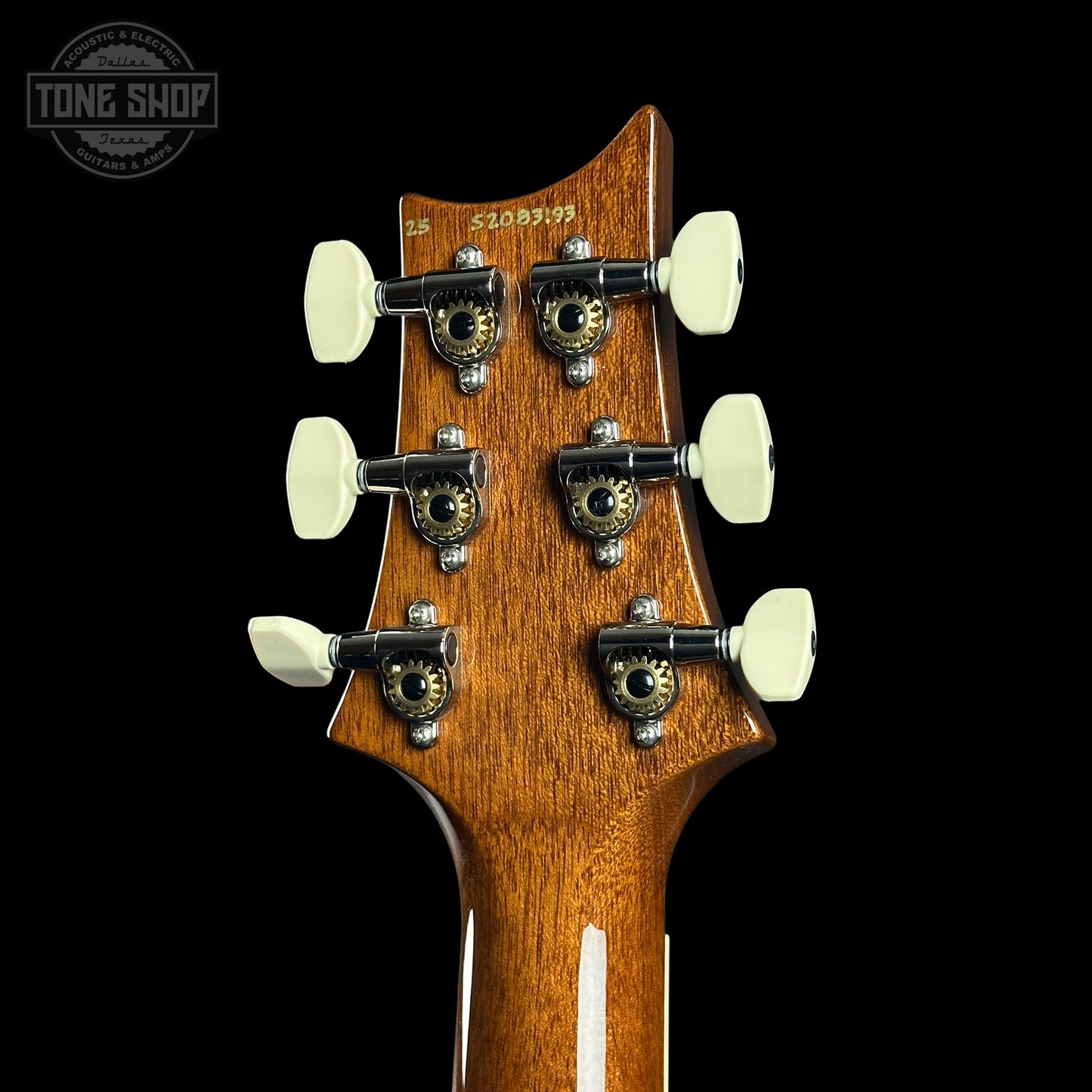 Close-up of a guitar headstock with tuning pegs on a black background, featuring the Tone Shop logo.