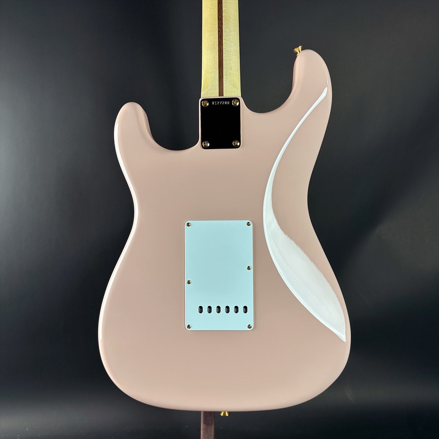 Electric guitar with a beige body and white pickguard on a dark background