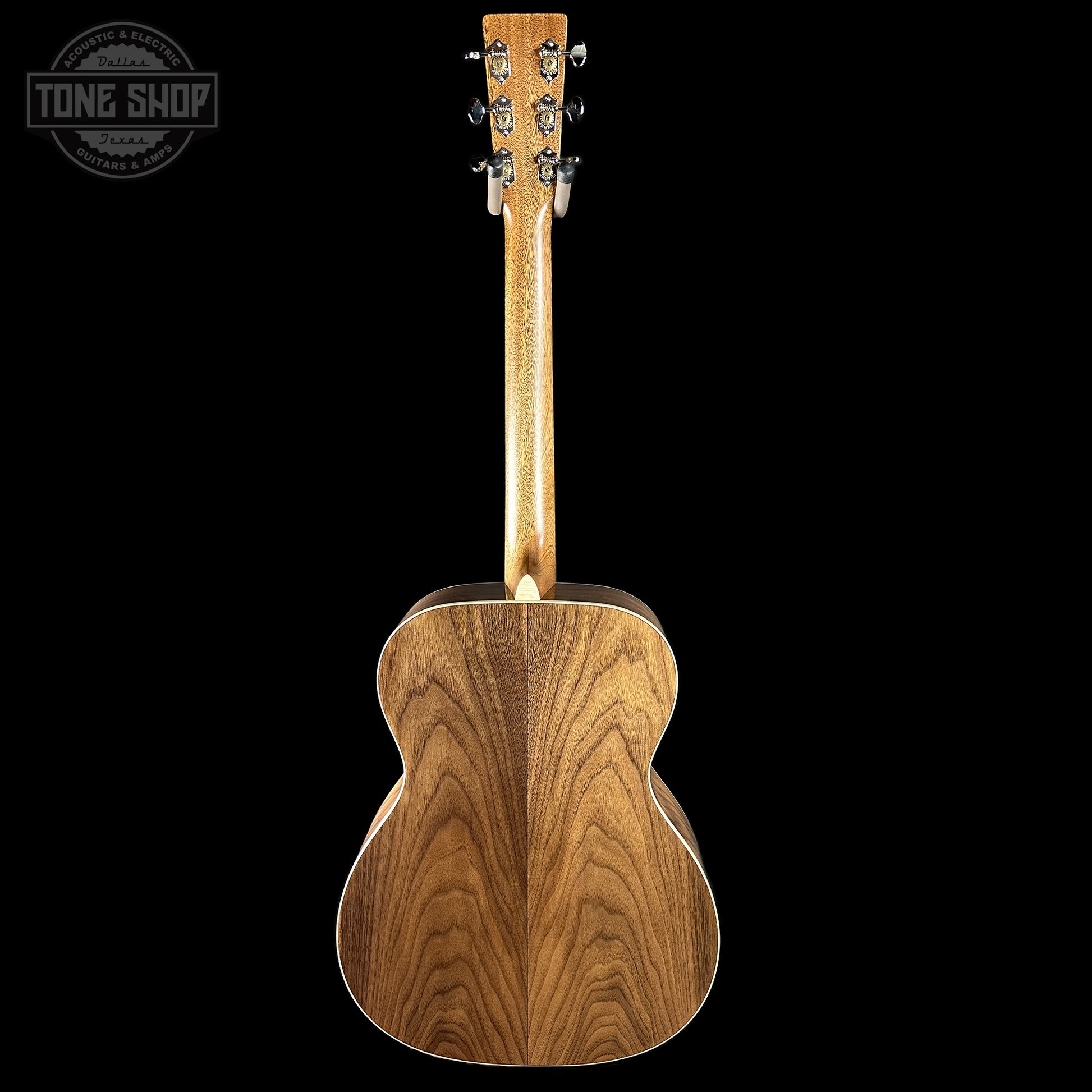 Back view of a wooden acoustic guitar with 'Tone Shop' logo.