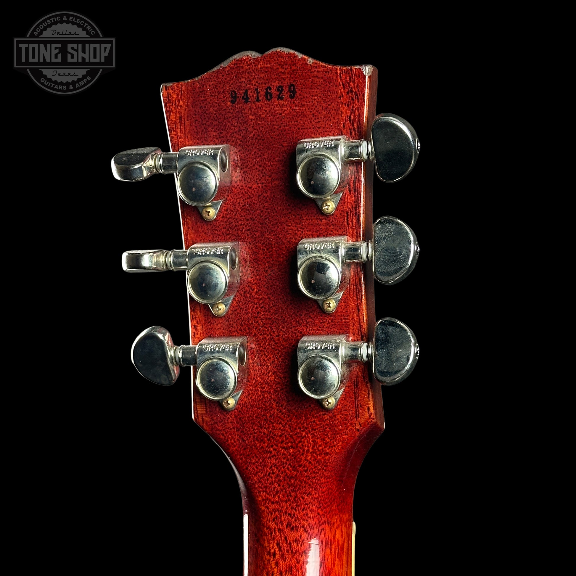 Close-up of a red guitar headstock with tuning pegs on a black background, featuring 'Tone Shop' logo.