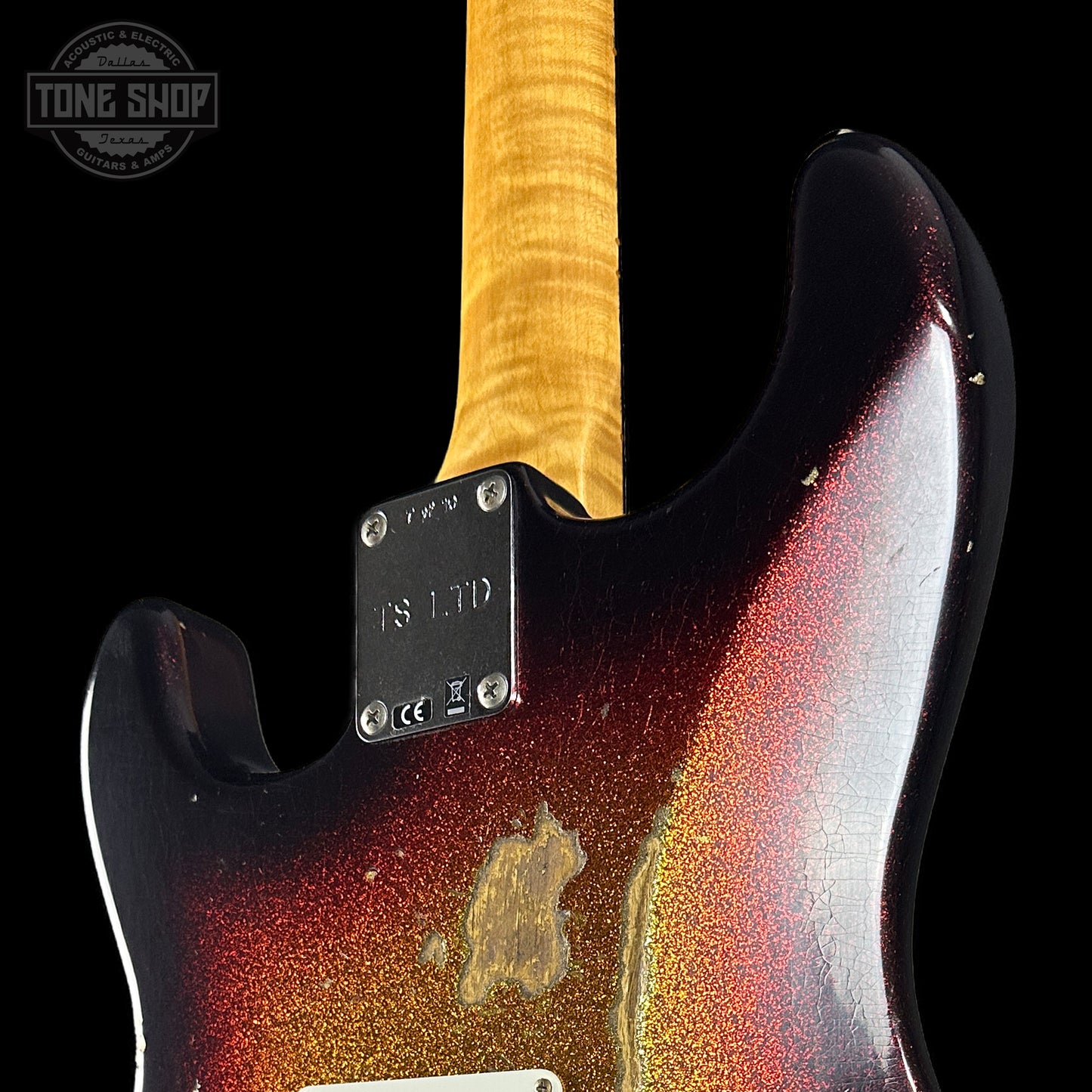 Close-up of a guitar with a red and black finish and a visible brand logo.