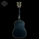 The back of a dark blue acoustic guitar with a glossy finish and white binding, shown against a solid black background. A Tone Shop watermark is visible in the top left corner.
