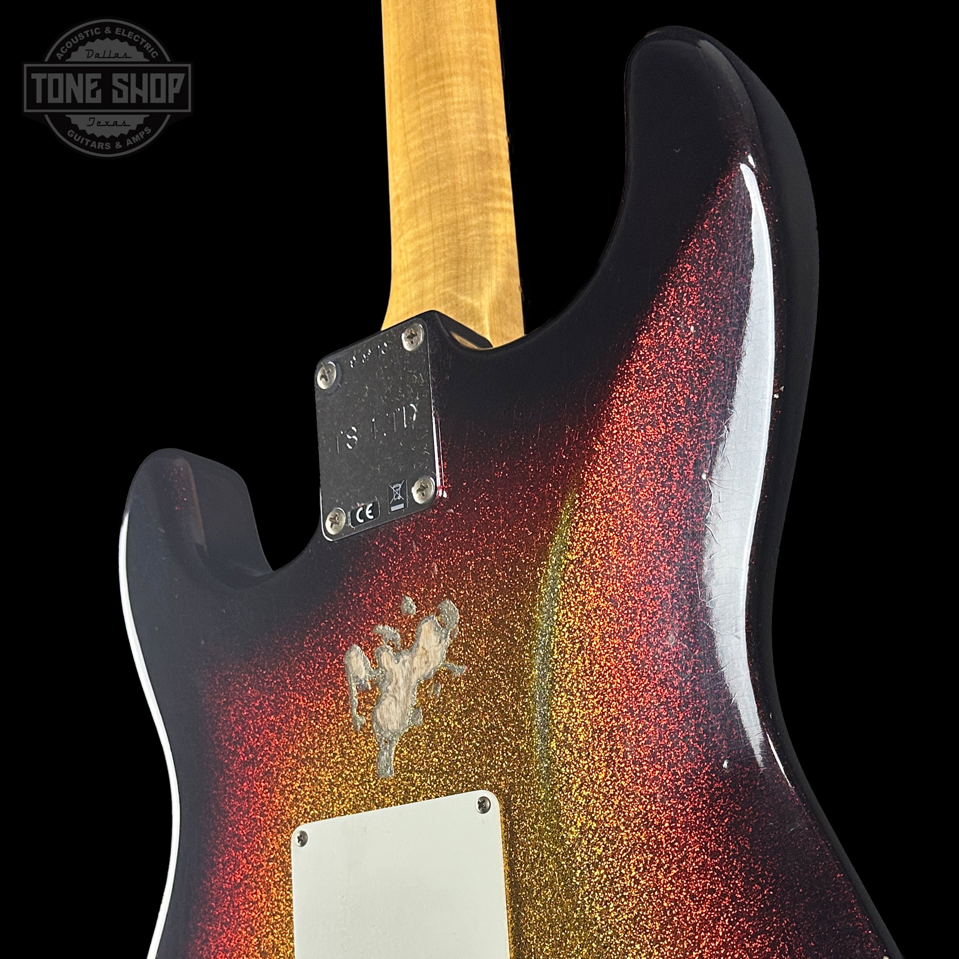 Close-up of a guitar with a multicolored glitter finish on a black background, featuring the Tone Shop logo.