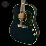 A close-up of a black acoustic guitar body with gold binding, a natural wood soundboard, and gold control knobs, shown against a black background with a Tone Shop watermark in the top left.