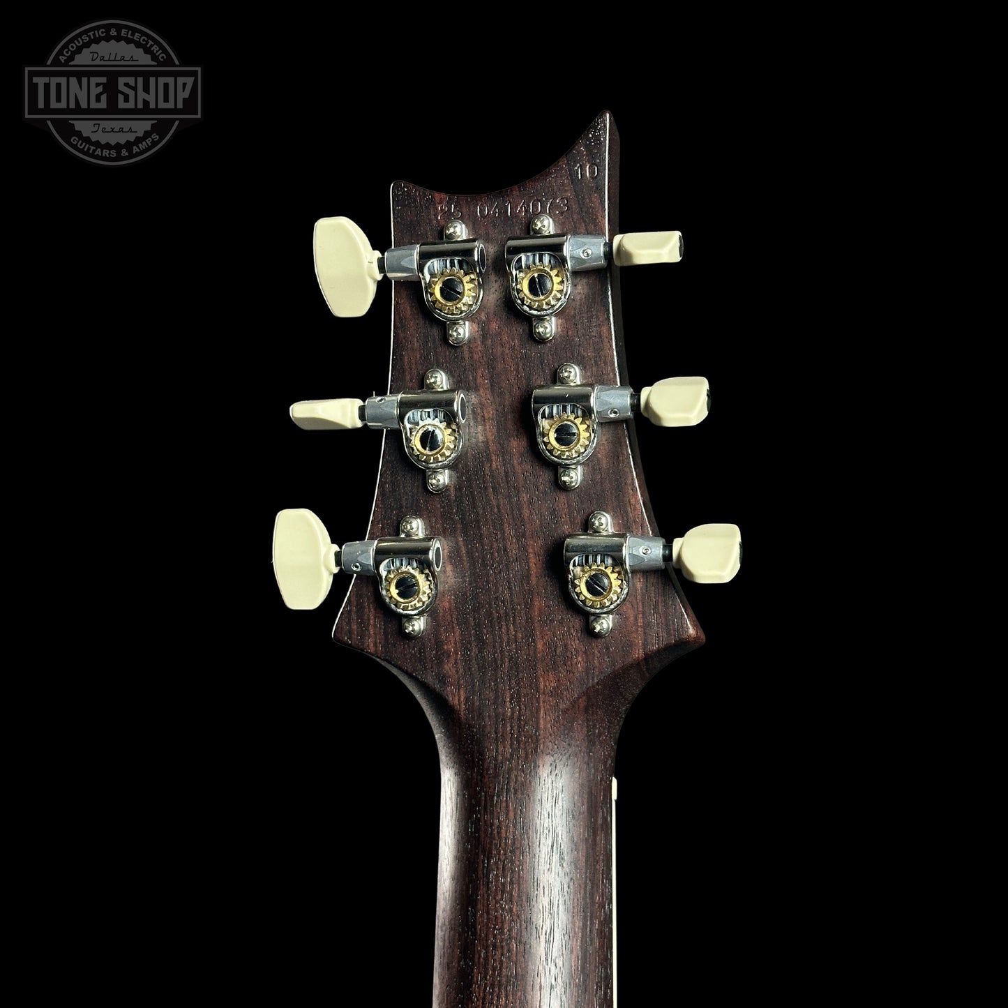 Close-up of a guitar headstock with tuning pegs on a black background, featuring the Tone Shop logo.