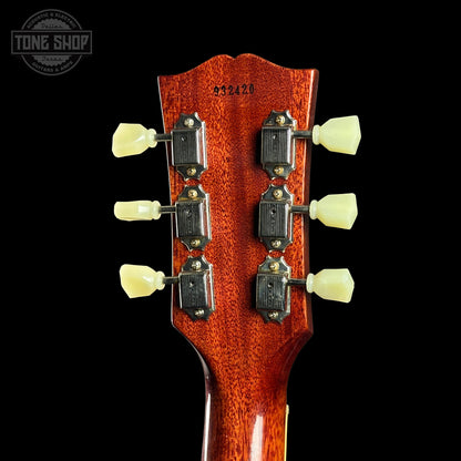 Close-up of a guitar headstock with tuning pegs on a black background, featuring the Tone Shop logo.