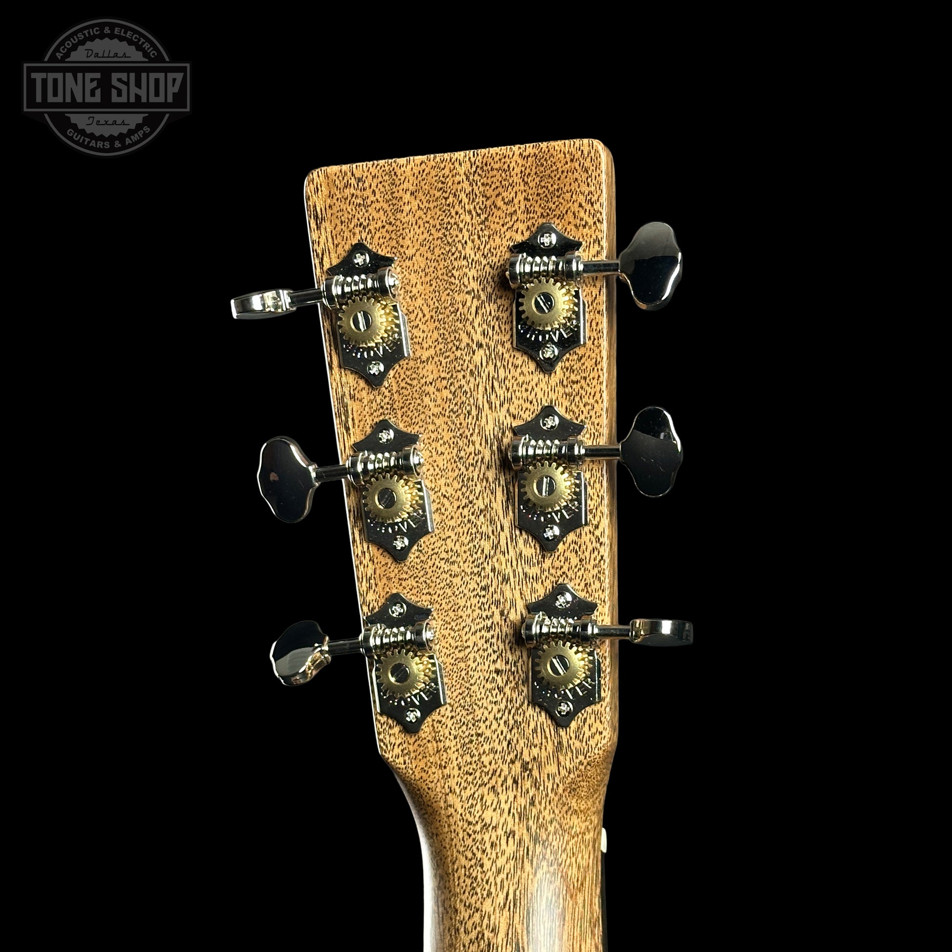 Close-up of a guitar headstock with tuning pegs on a black background, featuring the Tone Shop logo.