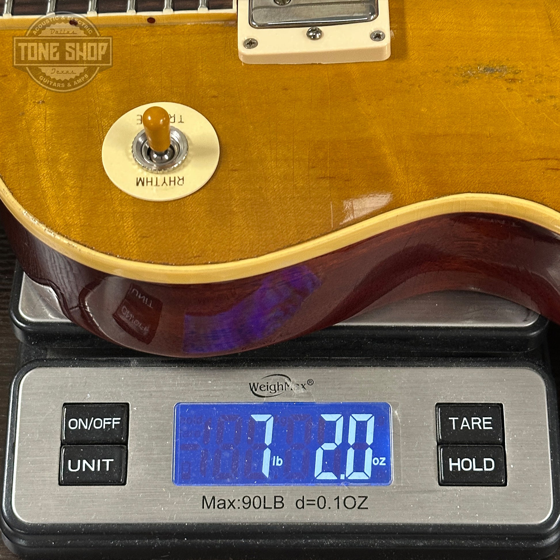 Electric guitar on a digital scale with 'Tone Shop' branding.