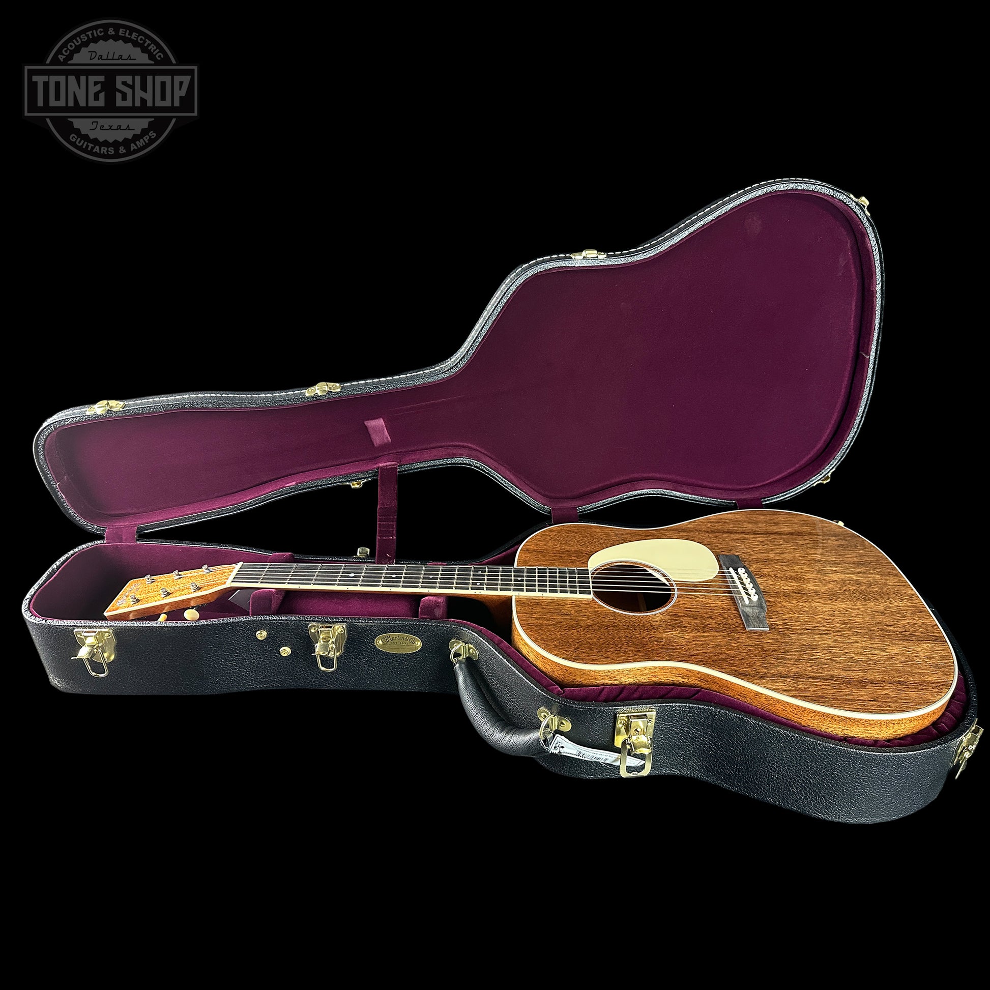 Acoustic guitar in an open case with 'Tone Shop' logo in the corner.