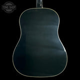 The back of an acoustic guitar with a glossy dark green finish and a thin cream-colored edge trim, shown against a solid black background.