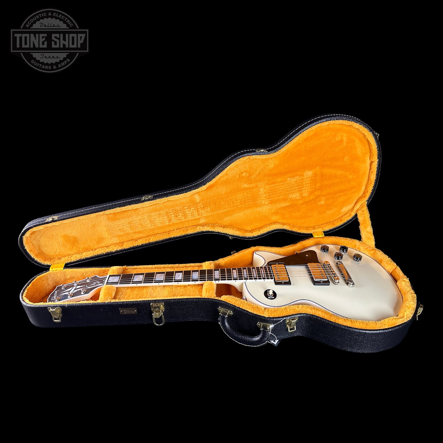 Electric guitar in an open case with a black and orange interior, brand 'Tone Shop' visible.