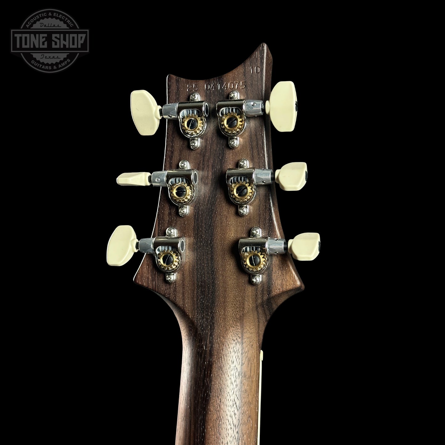 Close-up of a guitar headstock with tuning pegs on a black background, featuring the Tone Shop logo.