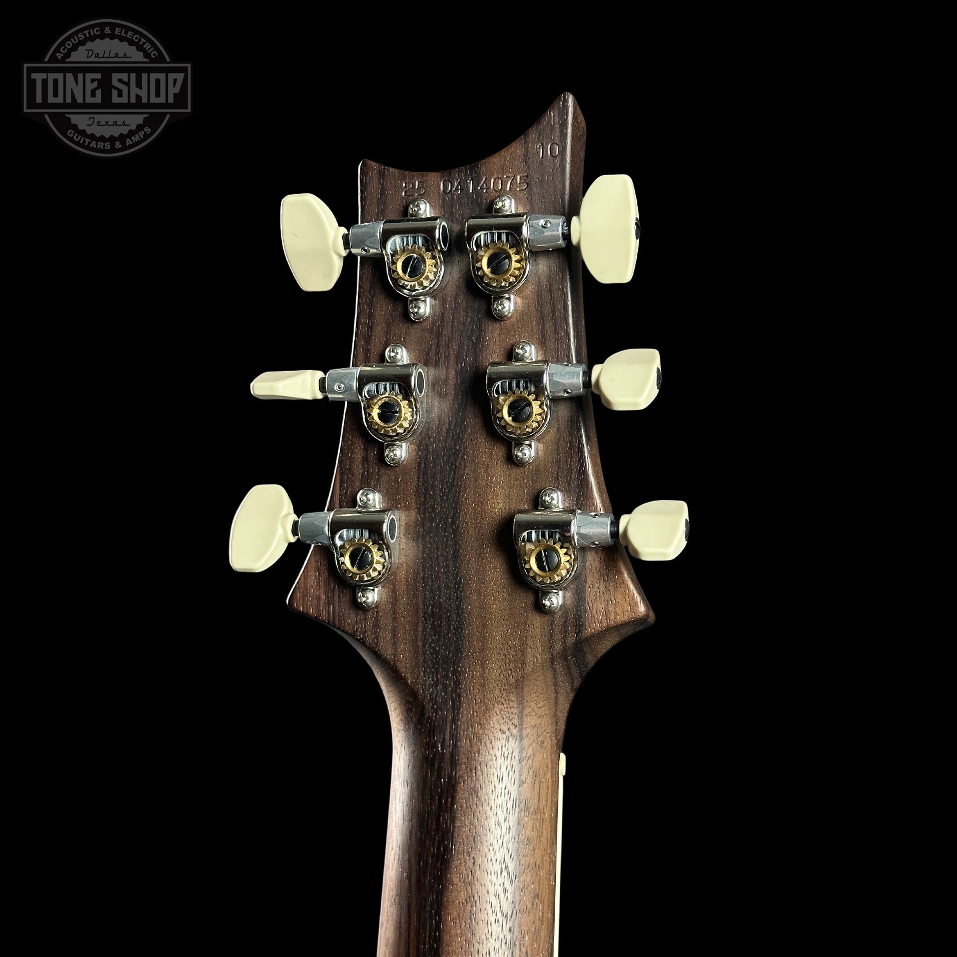 Close-up of a guitar headstock with tuning pegs on a black background, featuring the Tone Shop logo.
