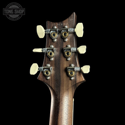 Close-up of a guitar headstock with tuning pegs on a black background, featuring the Tone Shop logo.
