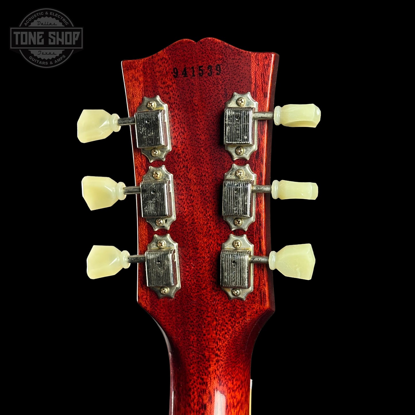 Close-up of a red guitar headstock with tuning pegs on a black background, featuring 'Tone Shop' logo.