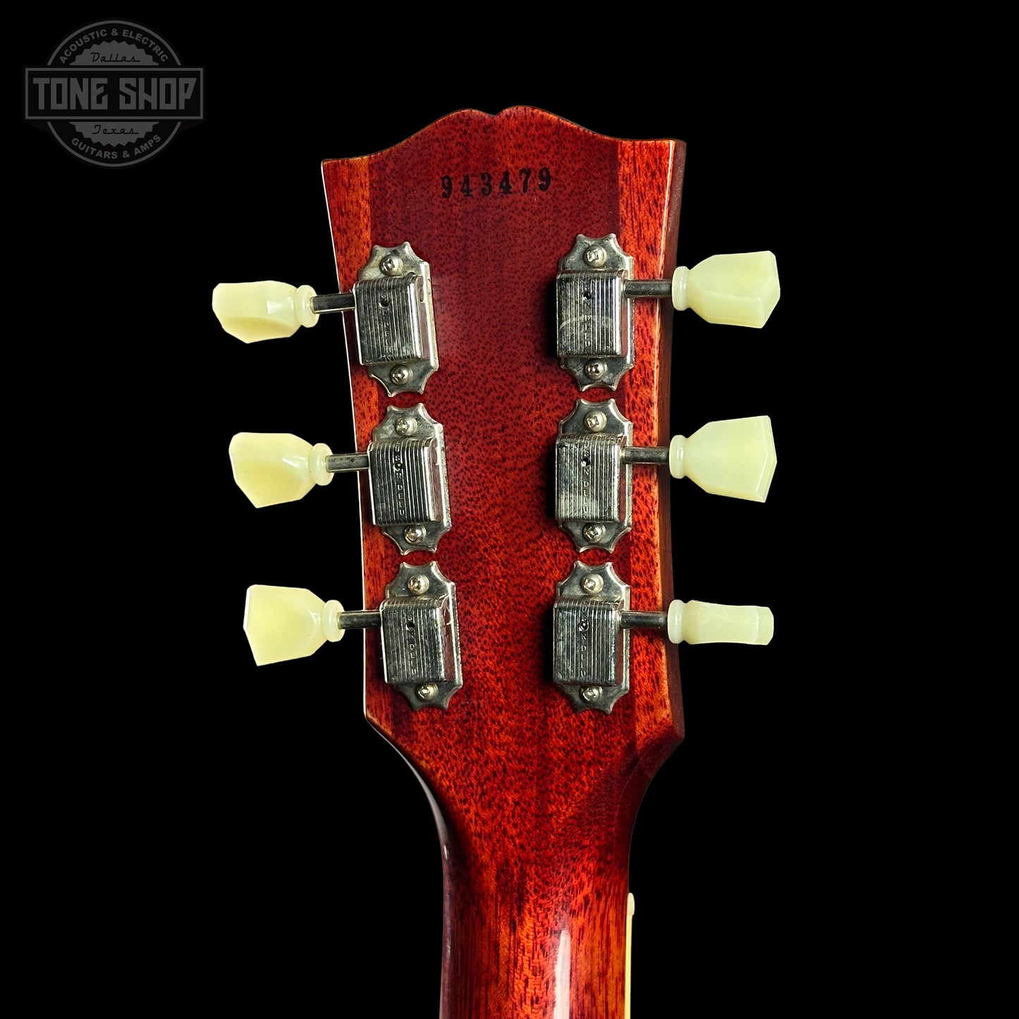 Close-up of a guitar's headstock with tuning pegs on a black background, featuring the Tone Shop logo.