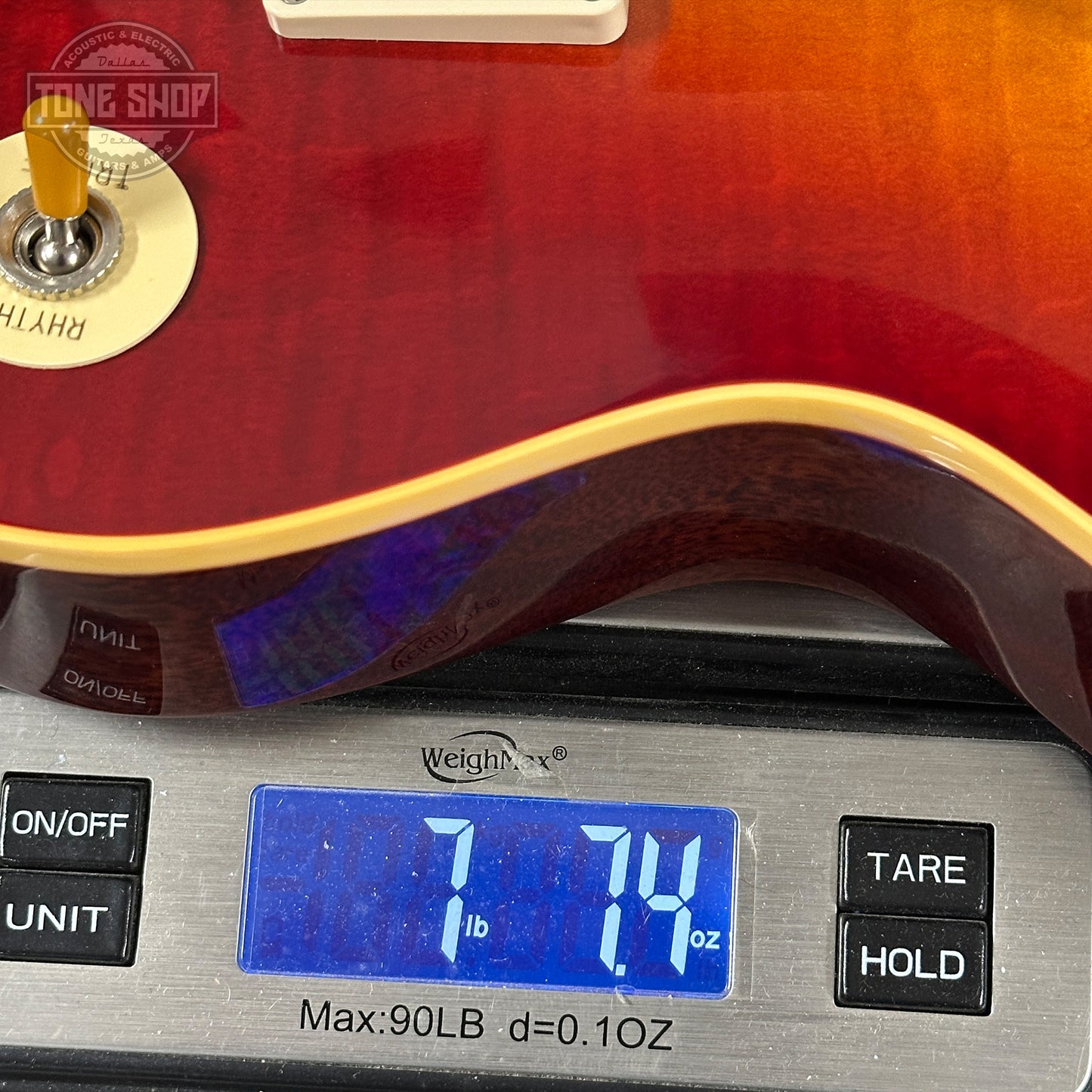 Red electric guitar on a digital scale displaying weight
