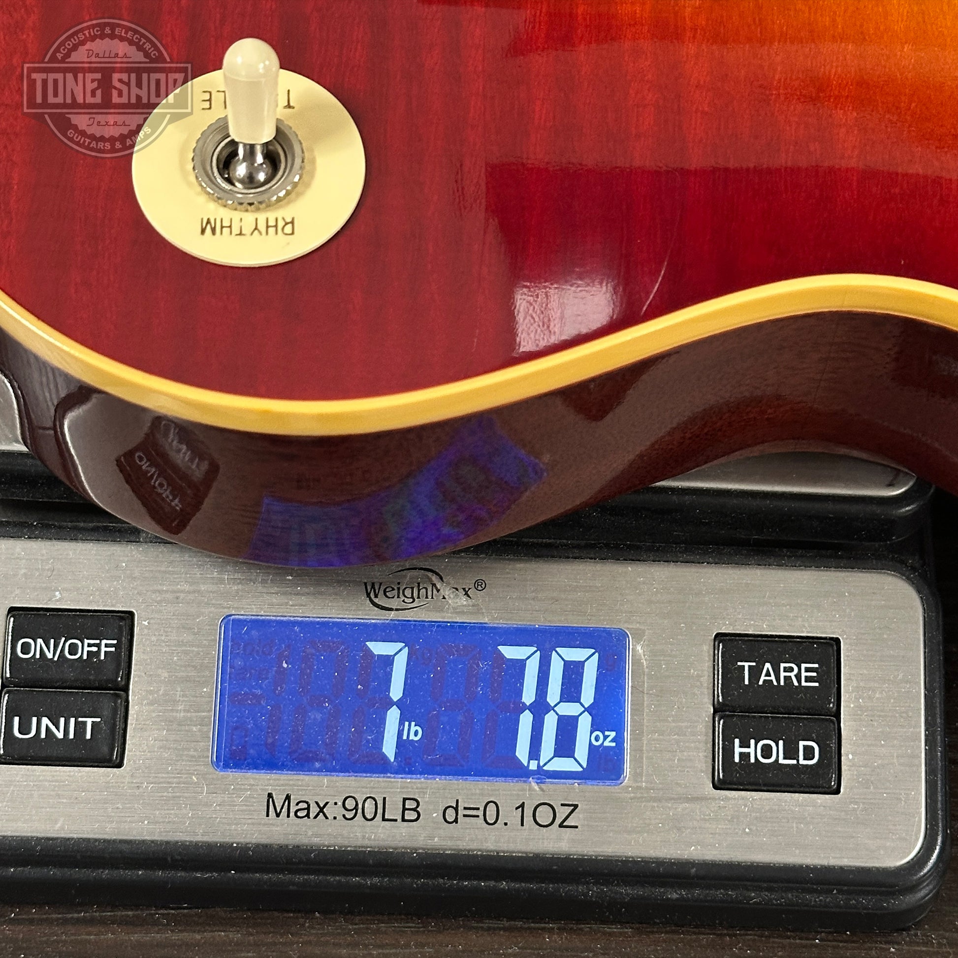 Red electric guitar on a digital scale displaying weight