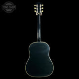 The back of an acoustic guitar with a glossy black finish and gold tuning pegs, shown against a solid black background with a Tone Shop watermark in the top left corner.
