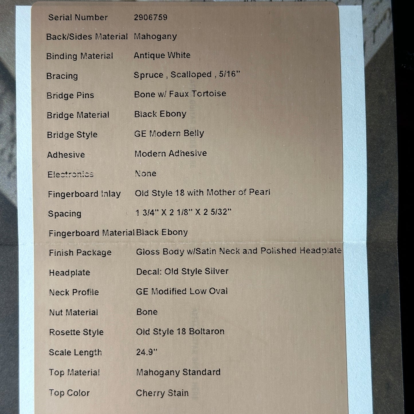 Cardboard label with detailed specifications of a guitar on a gray background