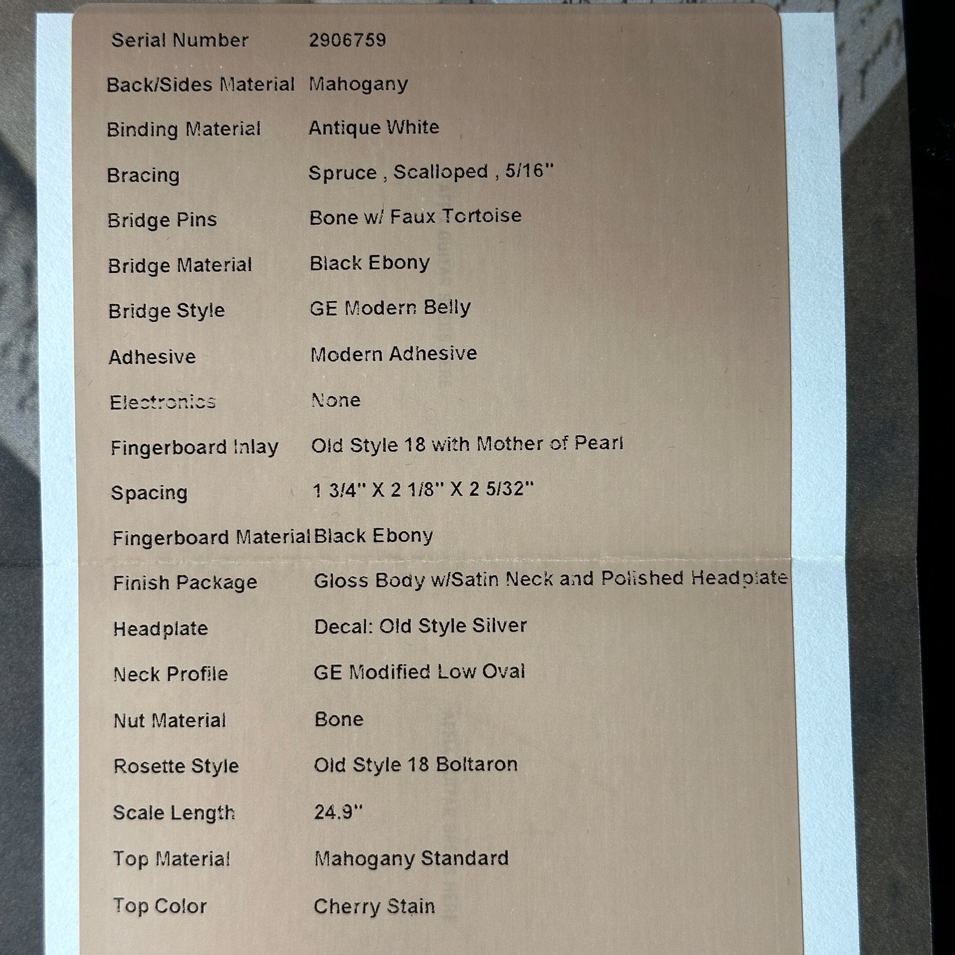 Cardboard label with detailed specifications of a guitar on a gray background