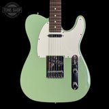 Green electric guitar with a white pickguard on a black background, featuring 'Tone Shop' branding.