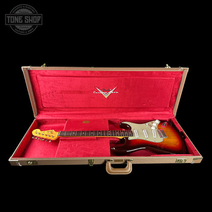 Electric guitar in a red-lined case with a visible brand logo on a black background.