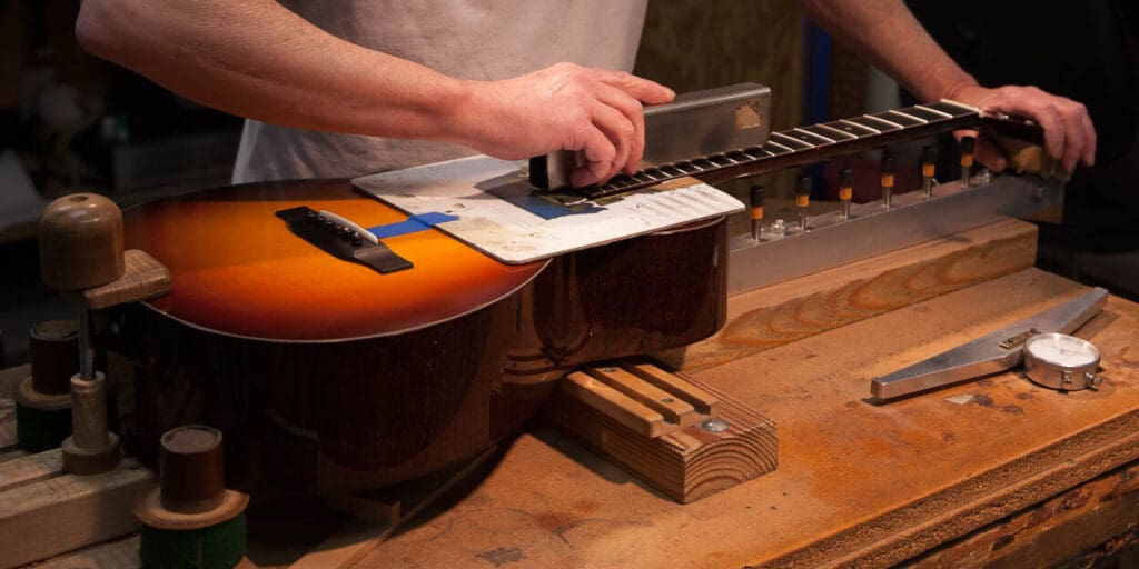 A luthier hand-building a Collings guitar at the workbench.
