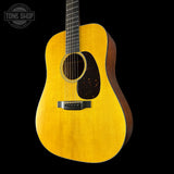 Acoustic guitar with a aged toner finish on a black background, featuring the Tone Shop logo.