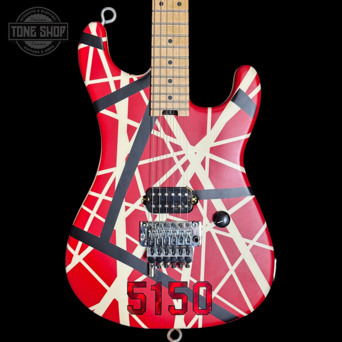Guitar with red and white design on a black background, featuring the 'Tone Shop' logo.