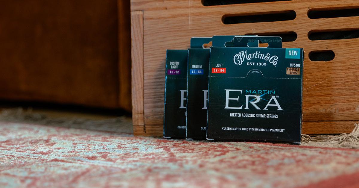 Martin Era Strings in green packaging on a colorful rug against a wooden background.