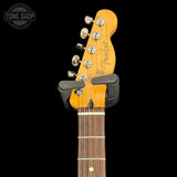 Fender guitar headstock with a black strap on a black background