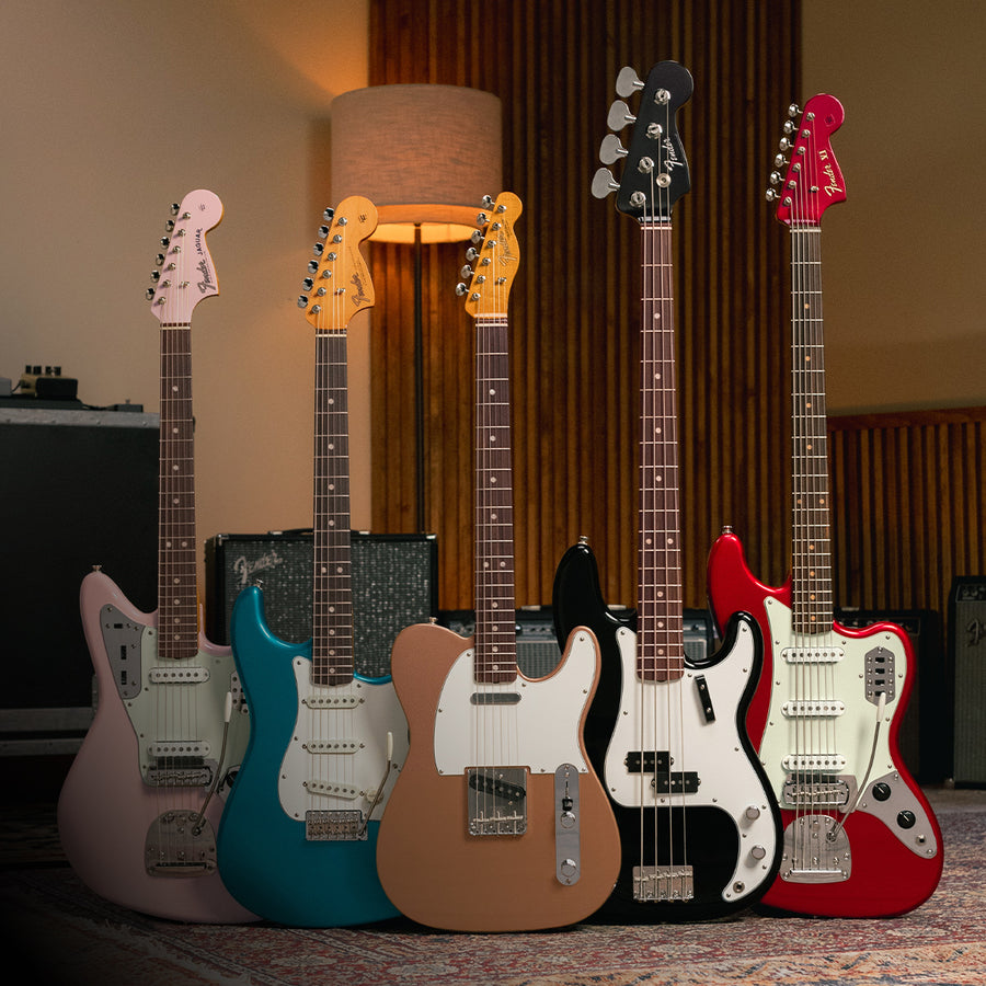A group of fender guitars in front of amps.