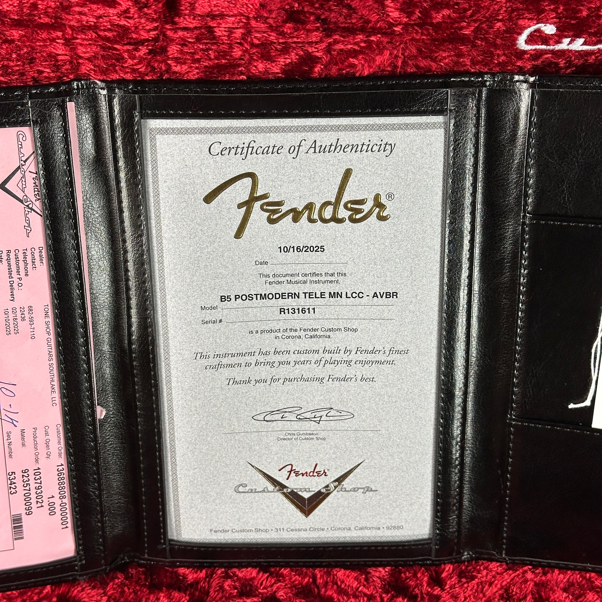 Fender certificate of authenticity in a black holder on a red textured surface