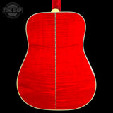 The back of an acoustic guitar with a vibrant red flamed maple top, a gold-toned center stripe, and a cream-colored edge binding, shown against a solid black background.