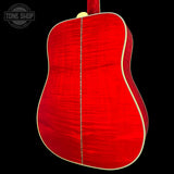 The back of a red acoustic guitar with a natural wood grain finish and cream-colored binding, shown against a solid black background. A Tone Shop watermark is visible in the top-left corner.