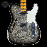 A custom electric guitar with a distressed black and silver paisley pattern on the body, a white pickguard, and a yellow maple neck, shown against a solid black background.