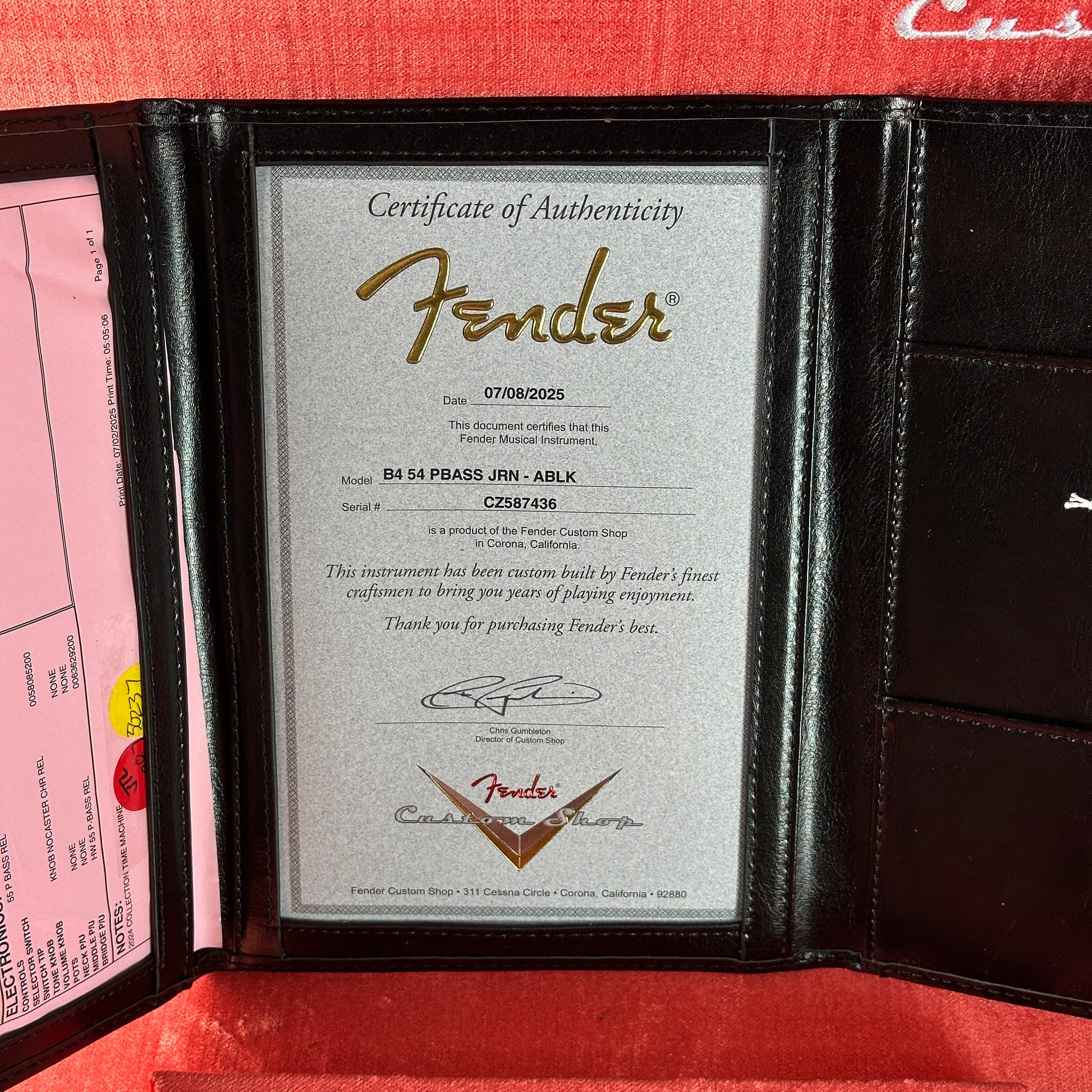 Fender certificate of authenticity in a black leather case with a red interior.