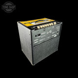 A black Fender Road Warrior 100W guitar amplifier cabinet shown from a three-quarters angle, displaying its rear panel controls and a yellow top handle cover, set against a solid black background.