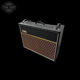 A black Vox guitar amplifier head with a brown diamond-patterned grille and gold logo, shown at an angle on a black background with a Tone Shop watermark in the top-left corner.
